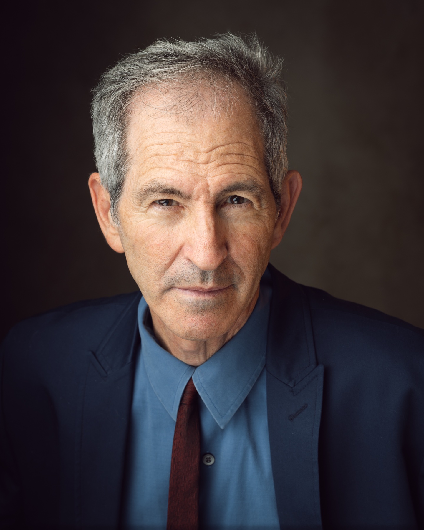 Professional acting headshot of a man in a navy suit and tie
