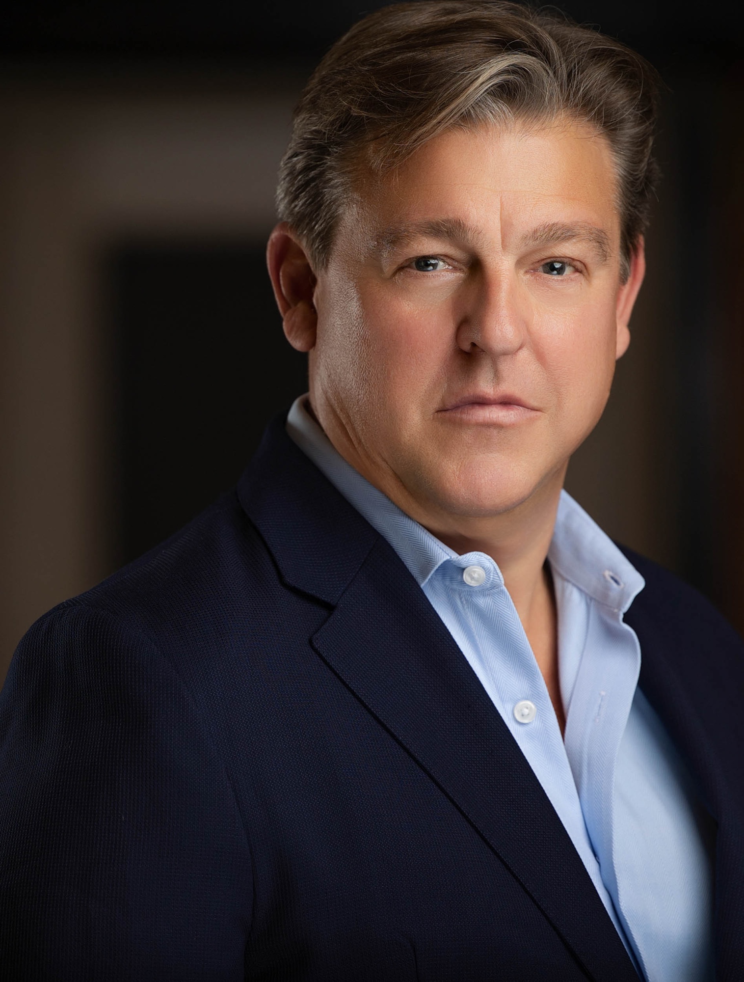 Actor headshot of a man in a navy blazer and light blue shirt