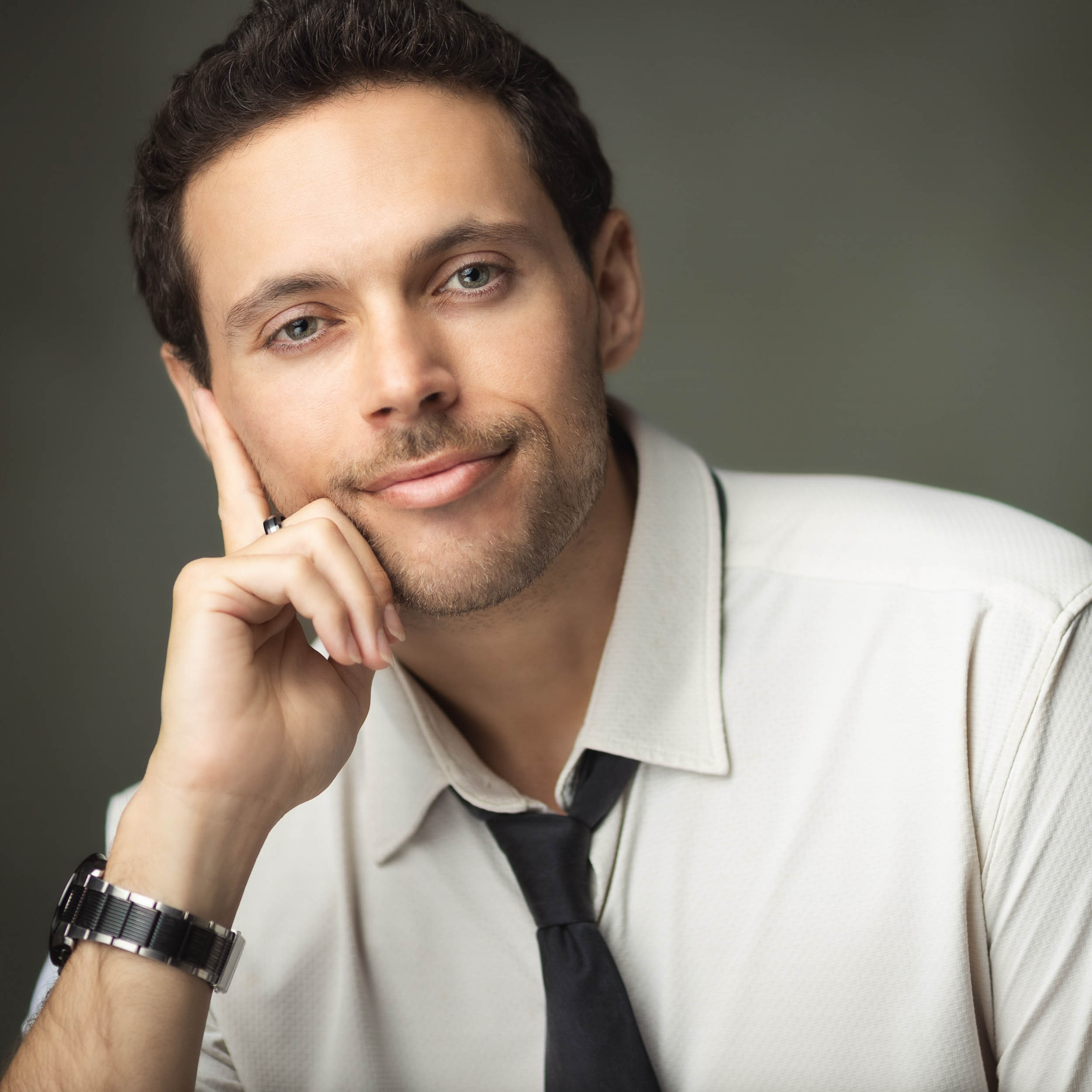 Professional headshot of a man in a white shirt and black tie