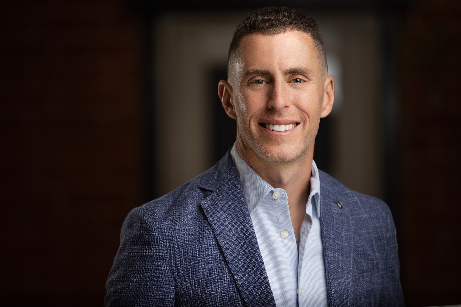 Corporate portrait of Eric Gold smiling in a textured blue blazer