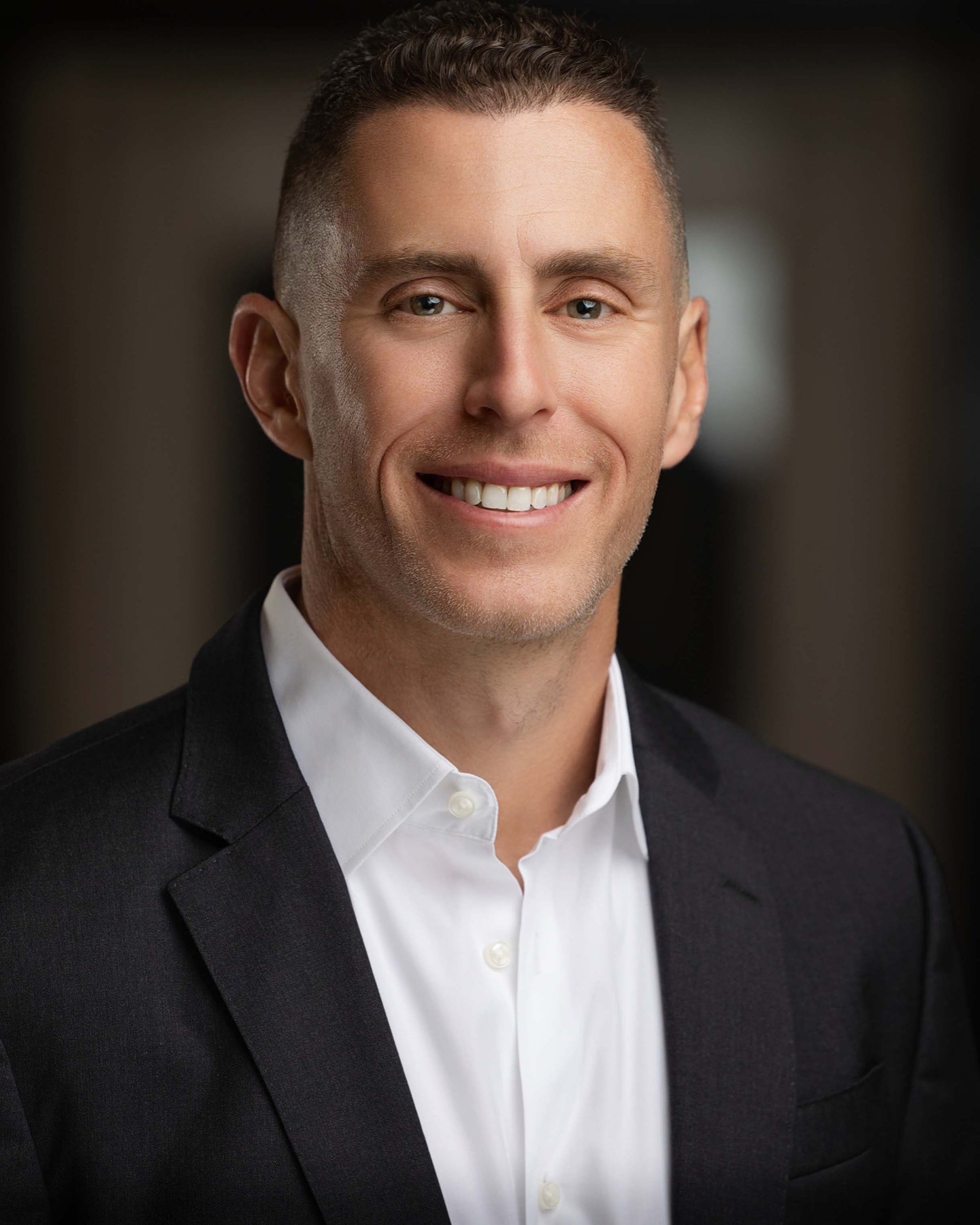 Corporate headshot of a man in a black suit and white shirt