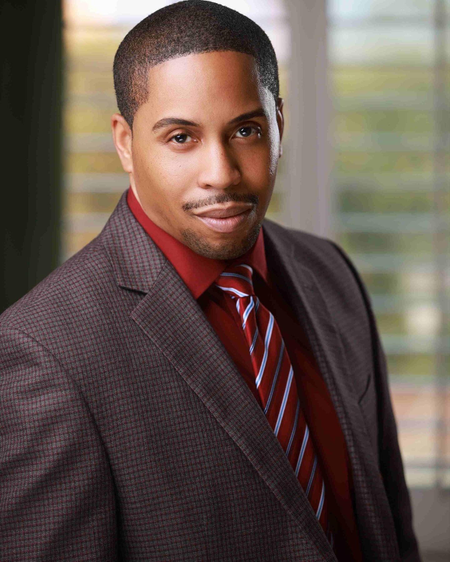Portrait of a man in a burgundy shirt and patterned suit