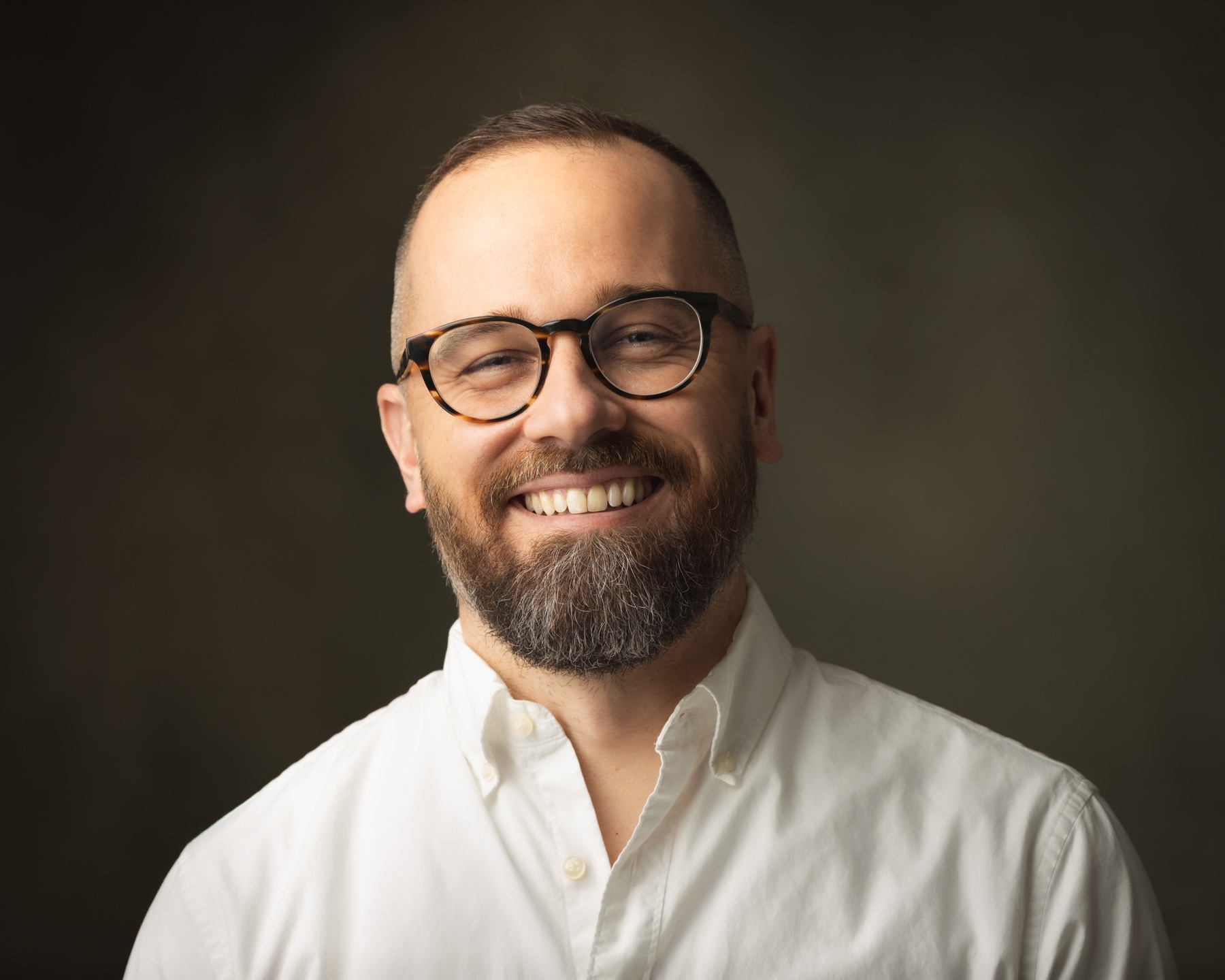 Landscape professional portrait of a smiling man in glasses and a white shirt
