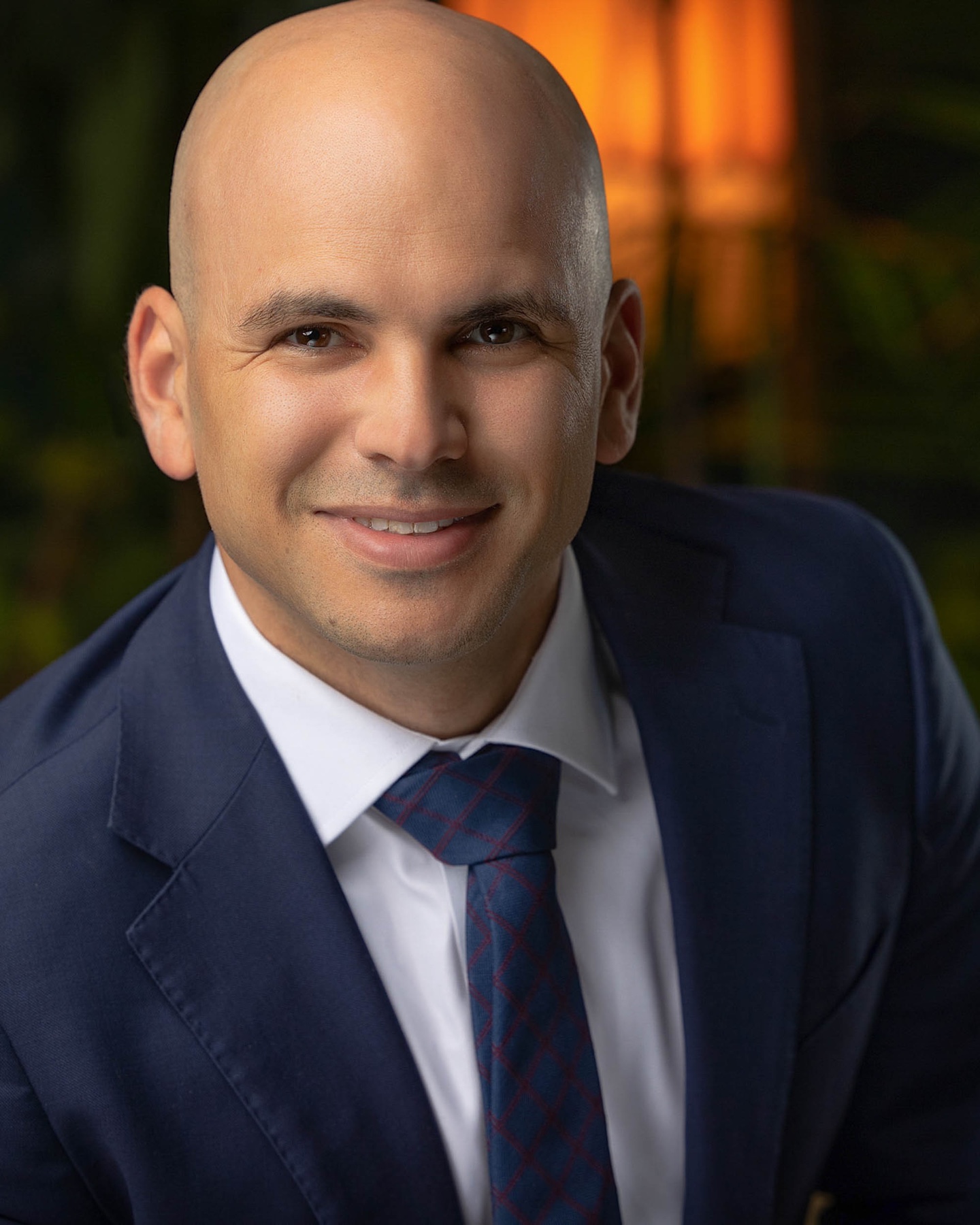 Corporate headshot of a smiling man in a navy suit and tie