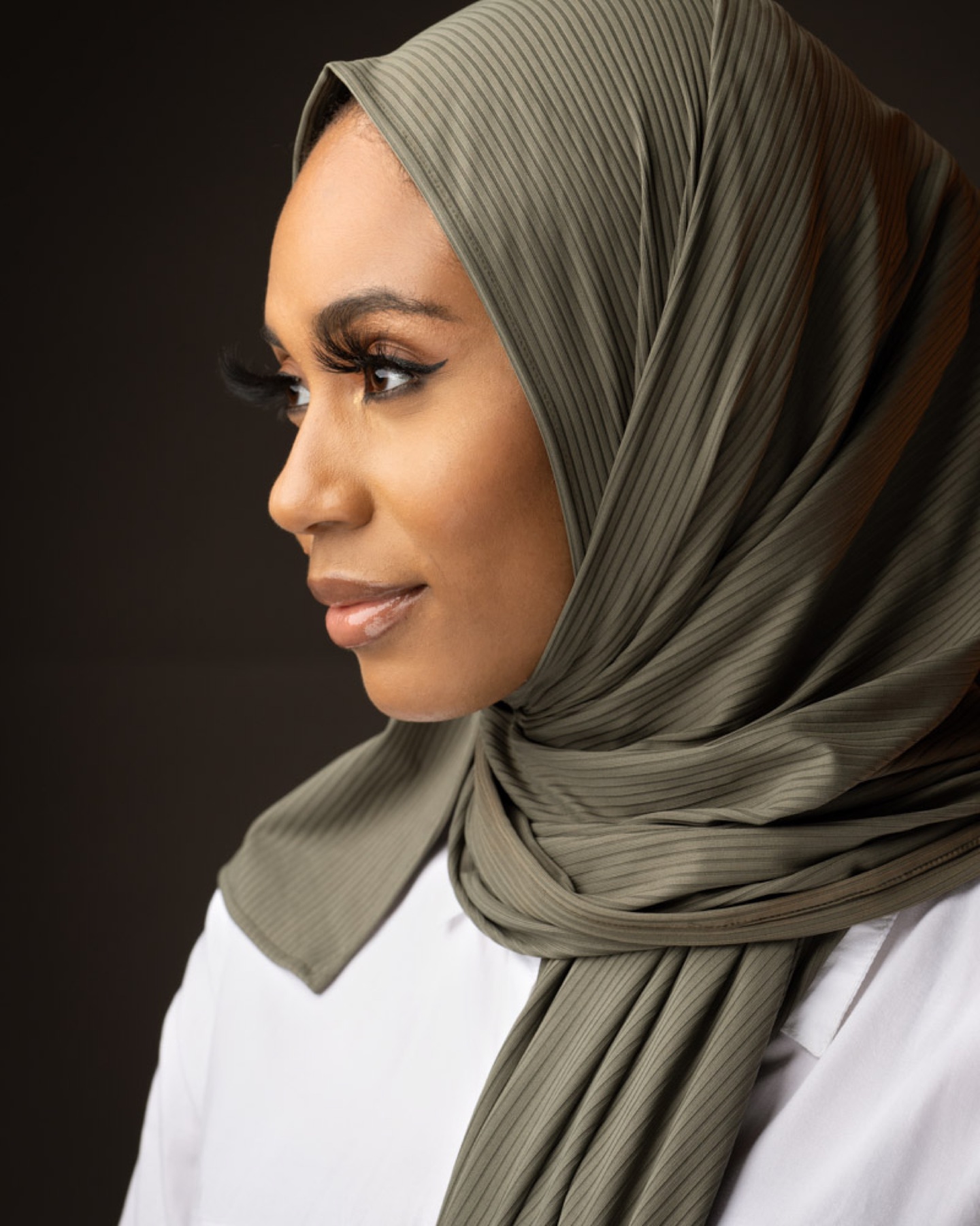 Profile headshot of a woman wearing an olive headscarf
