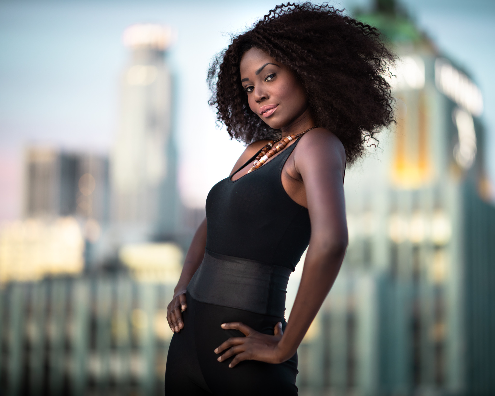 Woman in black photographed on a rooftop against the Los Angeles skyline at dusk