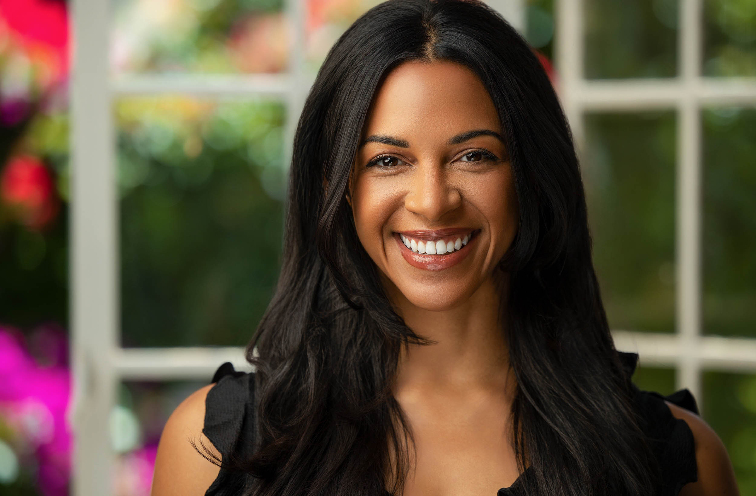 Smiling professional photographed beside a window and vivid flowers