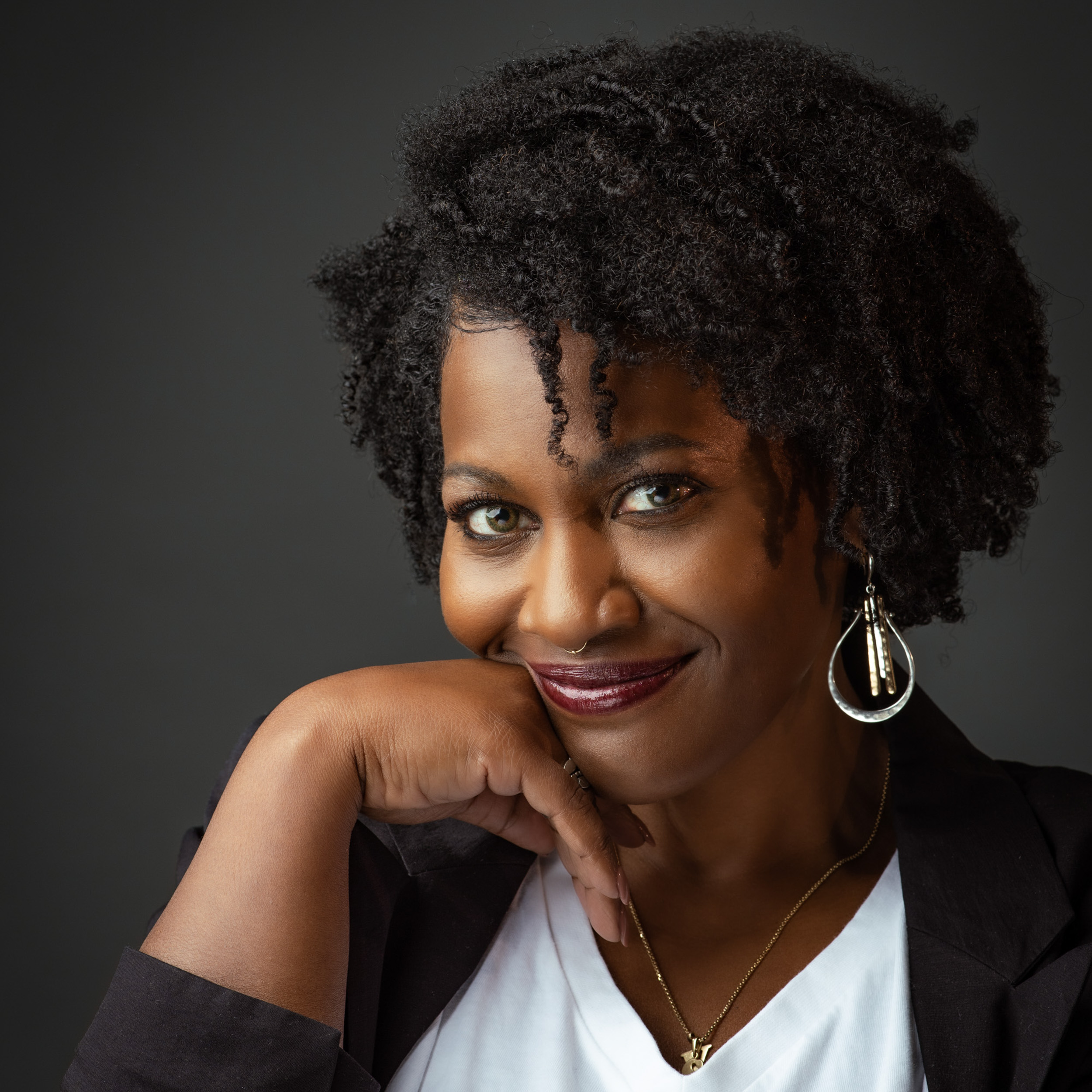 Signature portrait of a woman with natural curls resting her chin on her hand