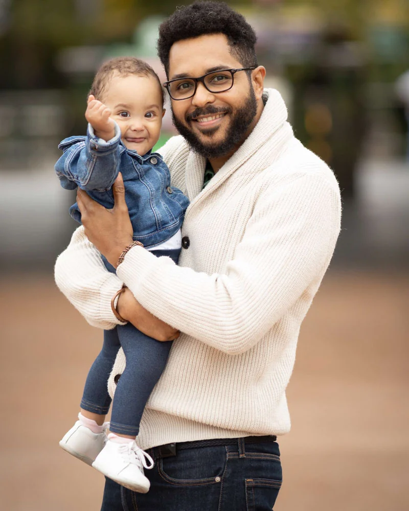 Wilhelm smiling while holding a baby outdoors